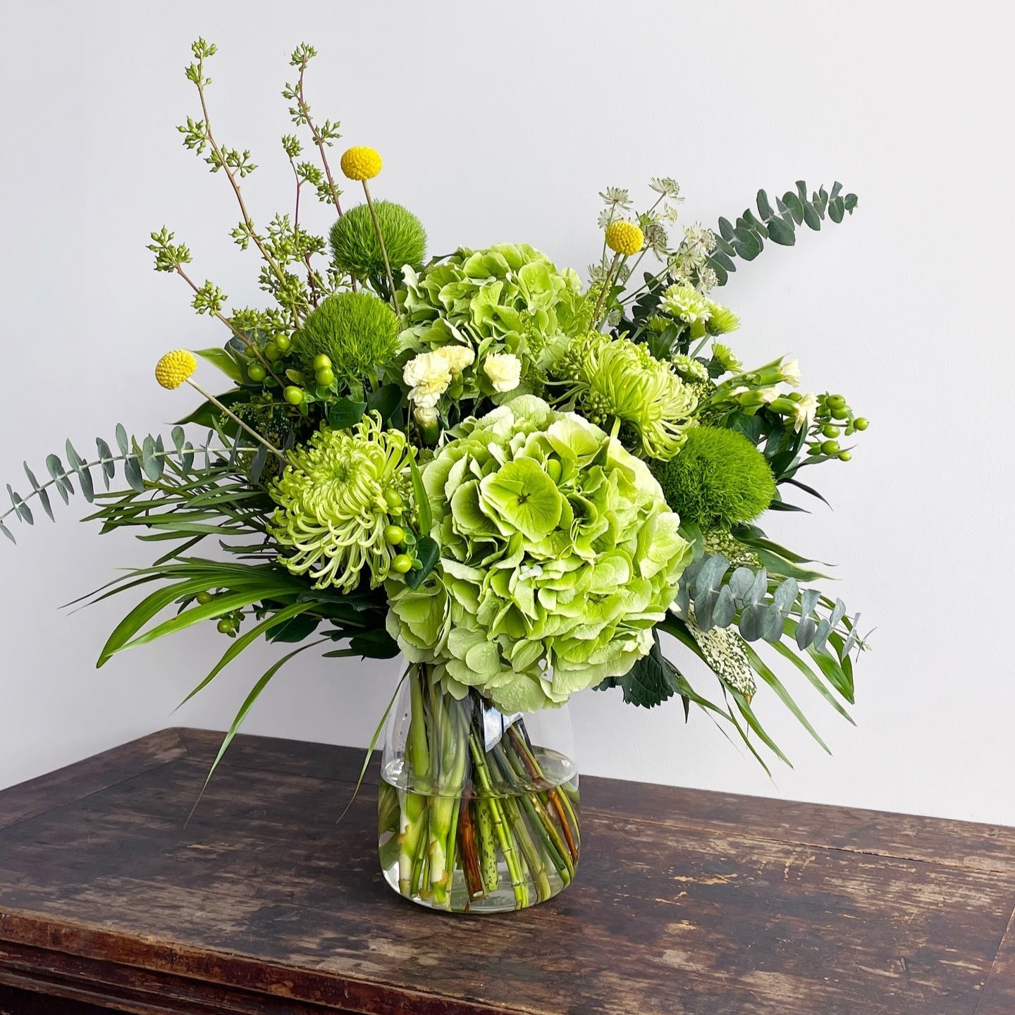 A refreshing all-green arrangement featuring lush hydrangeas and green ball dianthus, celebrating the beauty of nature in its purest form. With soft textures and rich tones, this bouquet brings calm, renewal, and a touch of earthy elegance to any space.