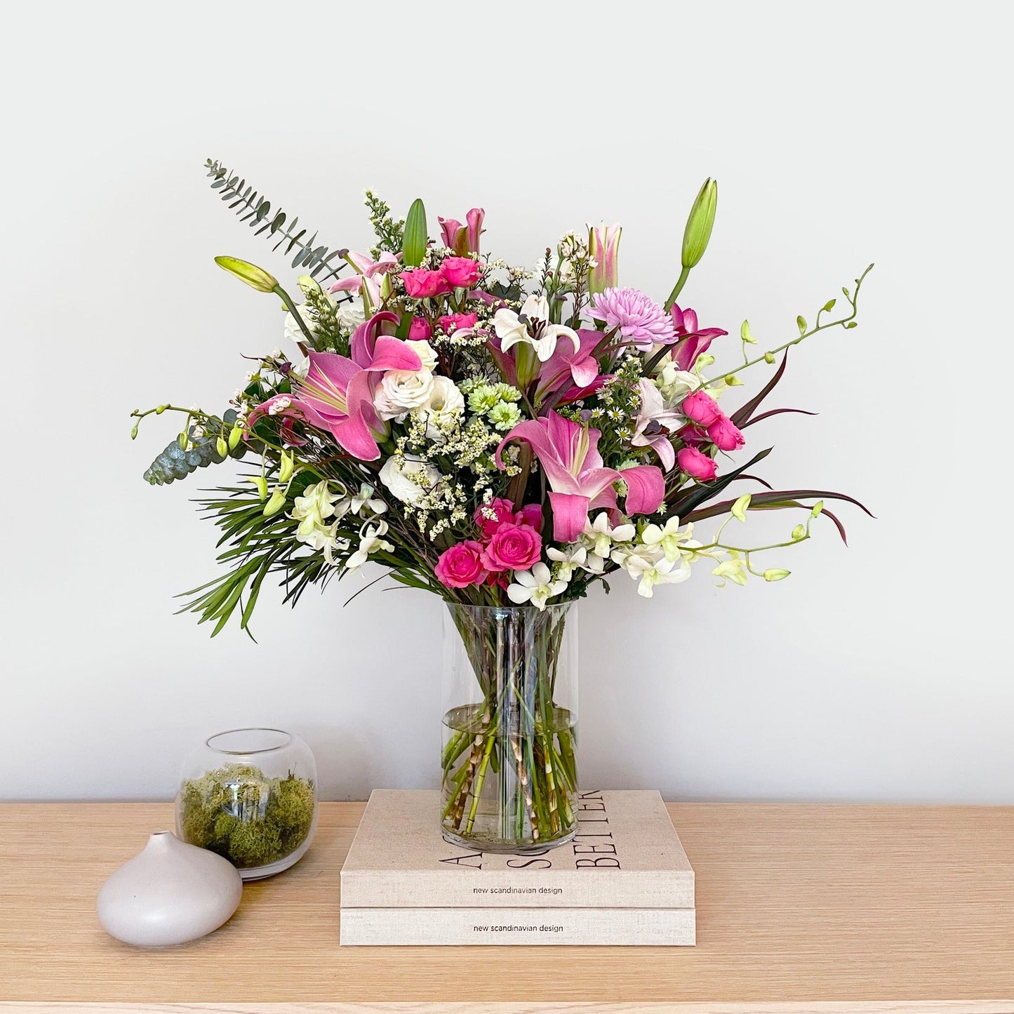 A soft, airy blend of lilies, carnations, eustoma (lisianthus), orchids, daisies, wax flowers, and silver dollar eucalyptus—this bouquet is a breath of fresh elegance. Its gentle hues and flowing greens create a peaceful, heartwarming arrangement that soothes and uplifts.