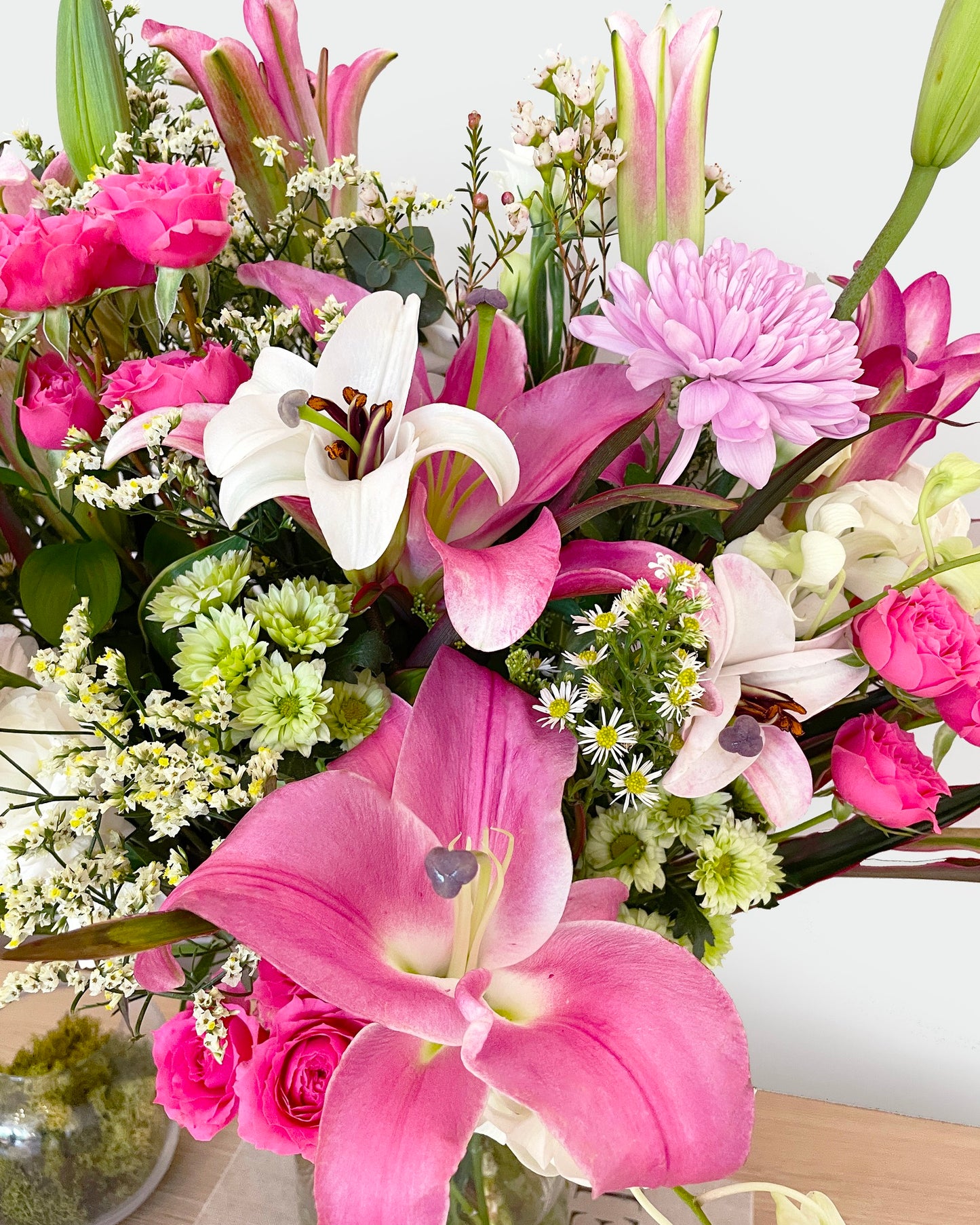 A soft, airy blend of lilies, carnations, eustoma (lisianthus), orchids, daisies, wax flowers, and silver dollar eucalyptus—this bouquet is a breath of fresh elegance. Its gentle hues and flowing greens create a peaceful, heartwarming arrangement that soothes and uplifts.