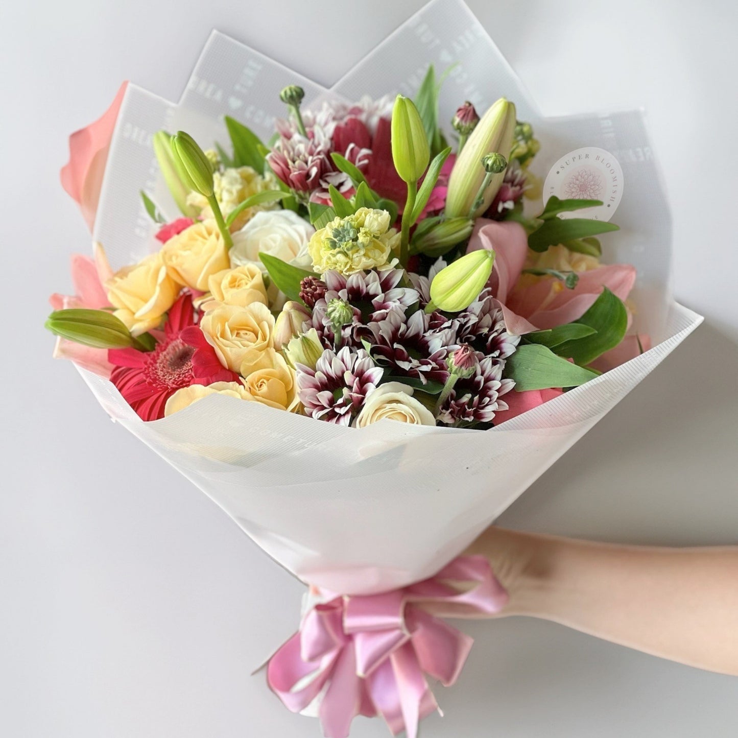 A captivating mix of timeless roses, elegant lilies, delicate lisianthus, and cheerful daisies, this arrangement radiates grace and charm. The soft petals and refreshing hues create a breathtaking floral experience, perfect for any celebration.