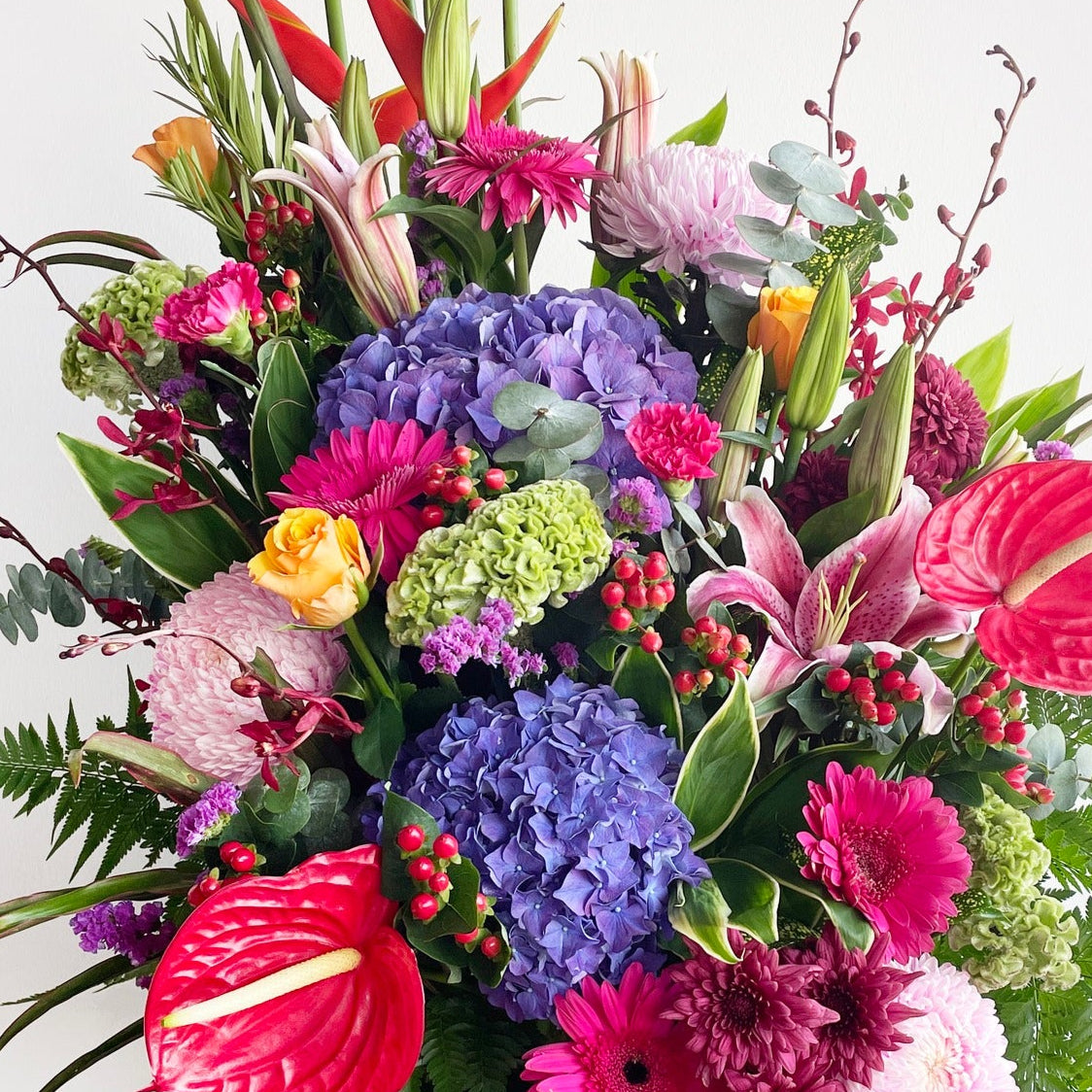 A stunning burst of nature’s finest, this vibrant bouquet blends anthurium, hydrangea, daisies, lilies, heliconia, roses, green fillers, and silver dollar eucalyptus. A rich mix of textures and multicolor tones, it’s crafted to dazzle and delight with every glance.