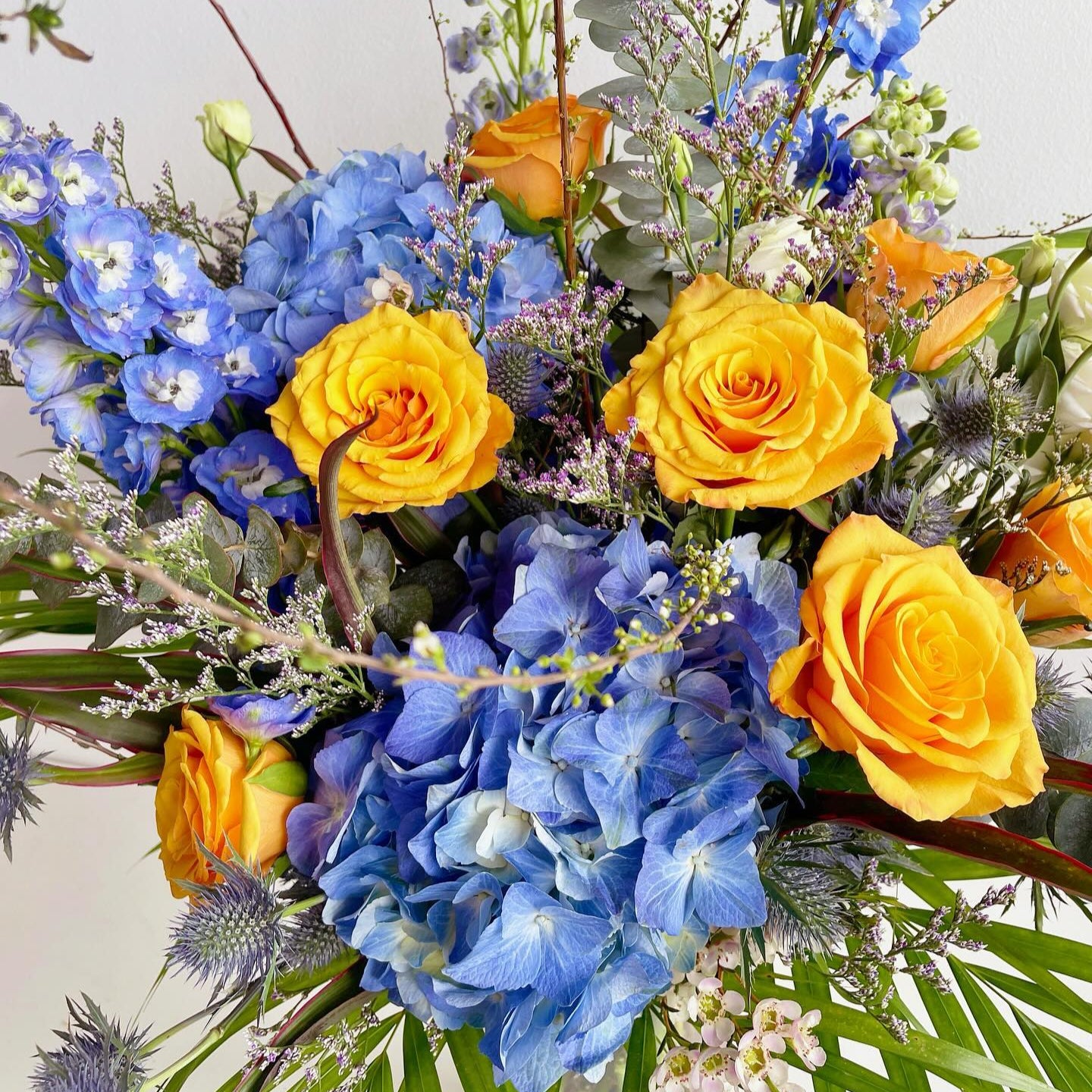 A vibrant harmony of colors, this bouquet features blue hydrangeas, blue orchids, and yellow roses. The contrast of golden warmth and cool blue tones creates a lively yet elegant arrangement—perfect for brightening moods and making bold, joyful statements.