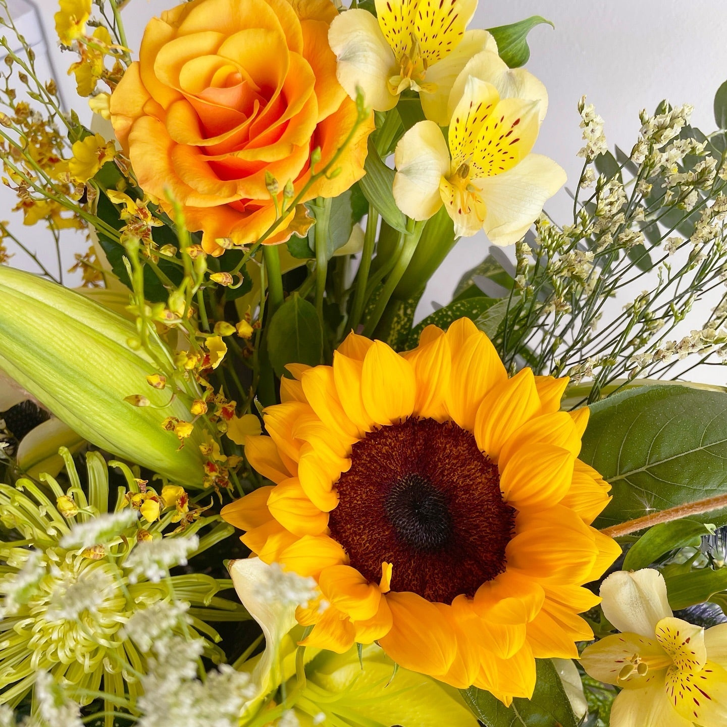 Bursting with sunshine and grace, this cheerful arrangement features sunflowers, orchids, roses, and lilies in radiant yellow and serene white tones. It brings warmth, positivity, and elegance—perfect for celebrations, thank-yous, or simply brightening someone's day.