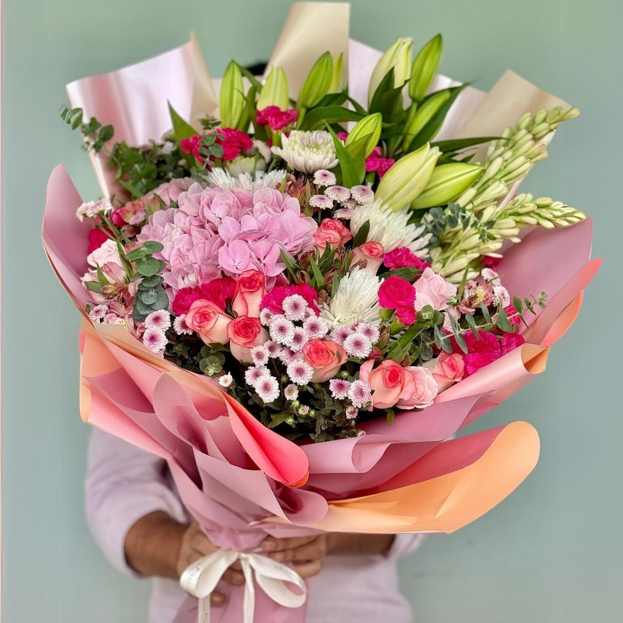 Experience the epitome of floral artistry with our Blissful Bloom Bouquet, a harmonious blend of Hydrangeas, Lilies, Daisies, Tuberoses, Eucalyptus, Roses, and Carnations. 